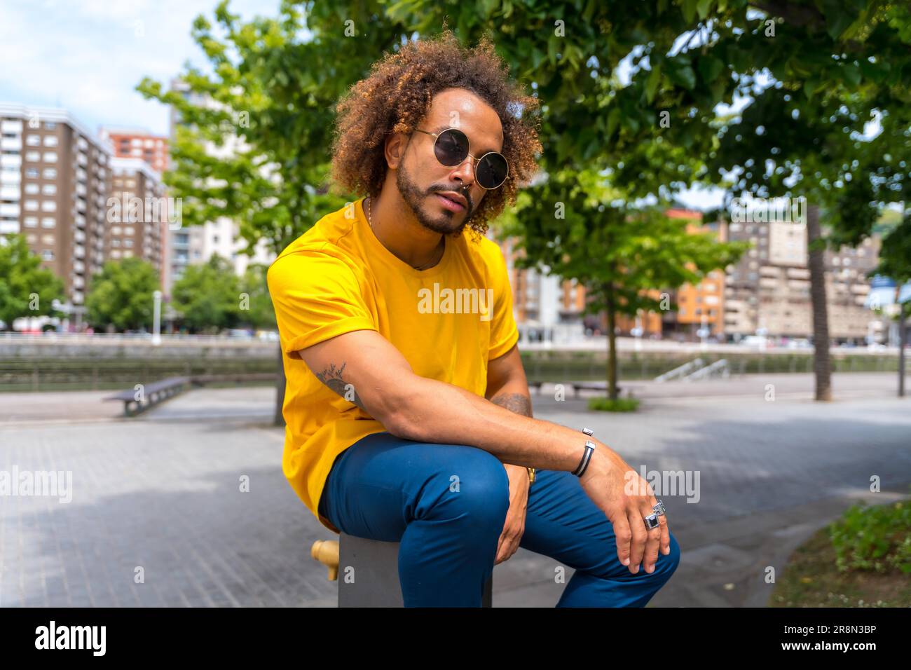 Retrato de un hombre afro-haired en una camiseta amarilla. Retrato en la ciudad sonriendo en vacaciones de verano Foto de stock