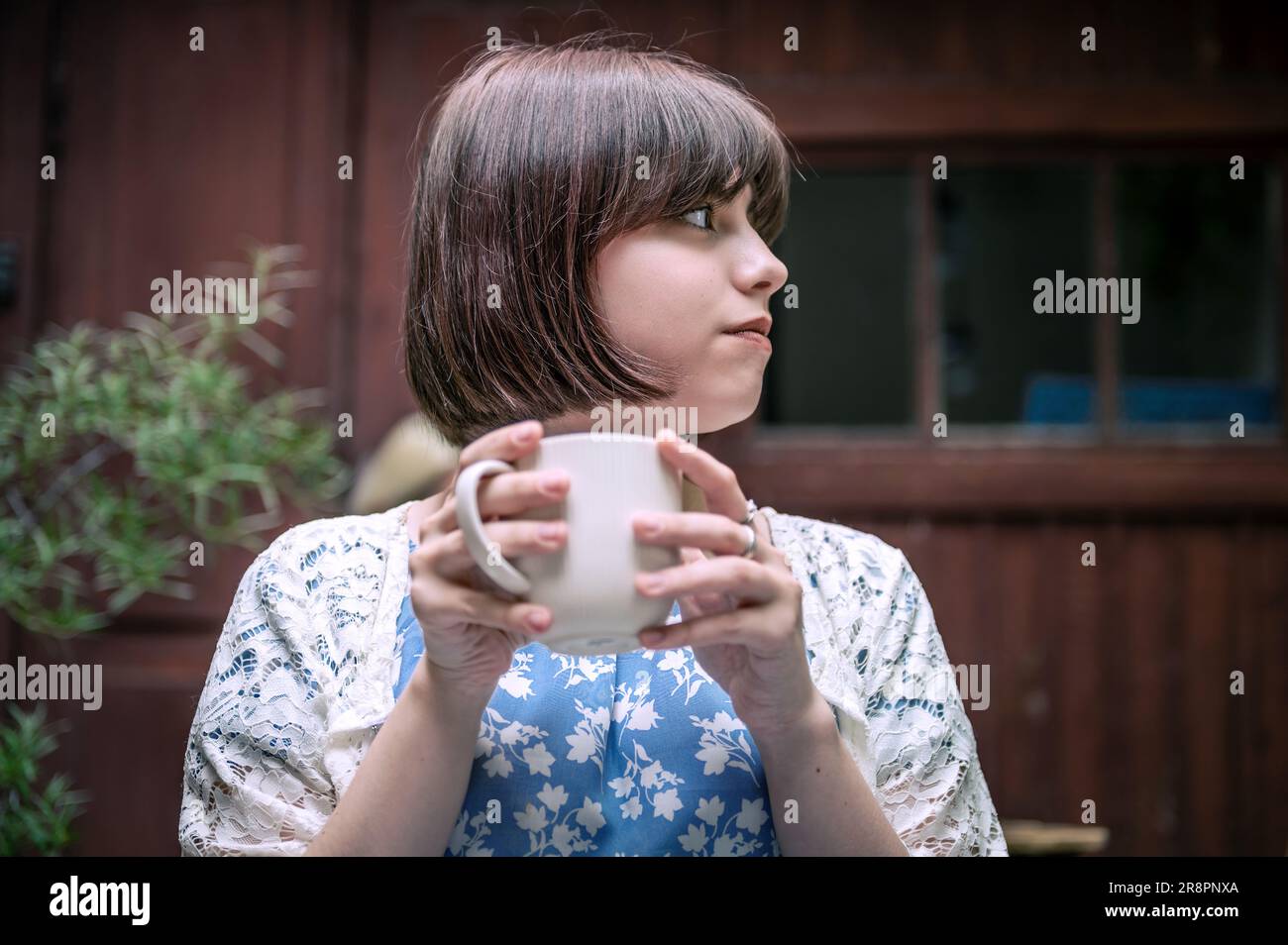 Muchacha adolescente feliz con taza bebiendo cacao en la terraza del café de la calle de la ciudad. Concepto de bebidas y personas. Adolescente bebiendo en café Foto de stock