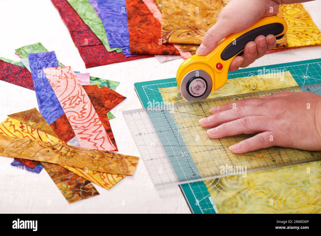 Procese las piezas de tela cortando con un cortador giratorio en la alfombrilla usando regla Foto de stock