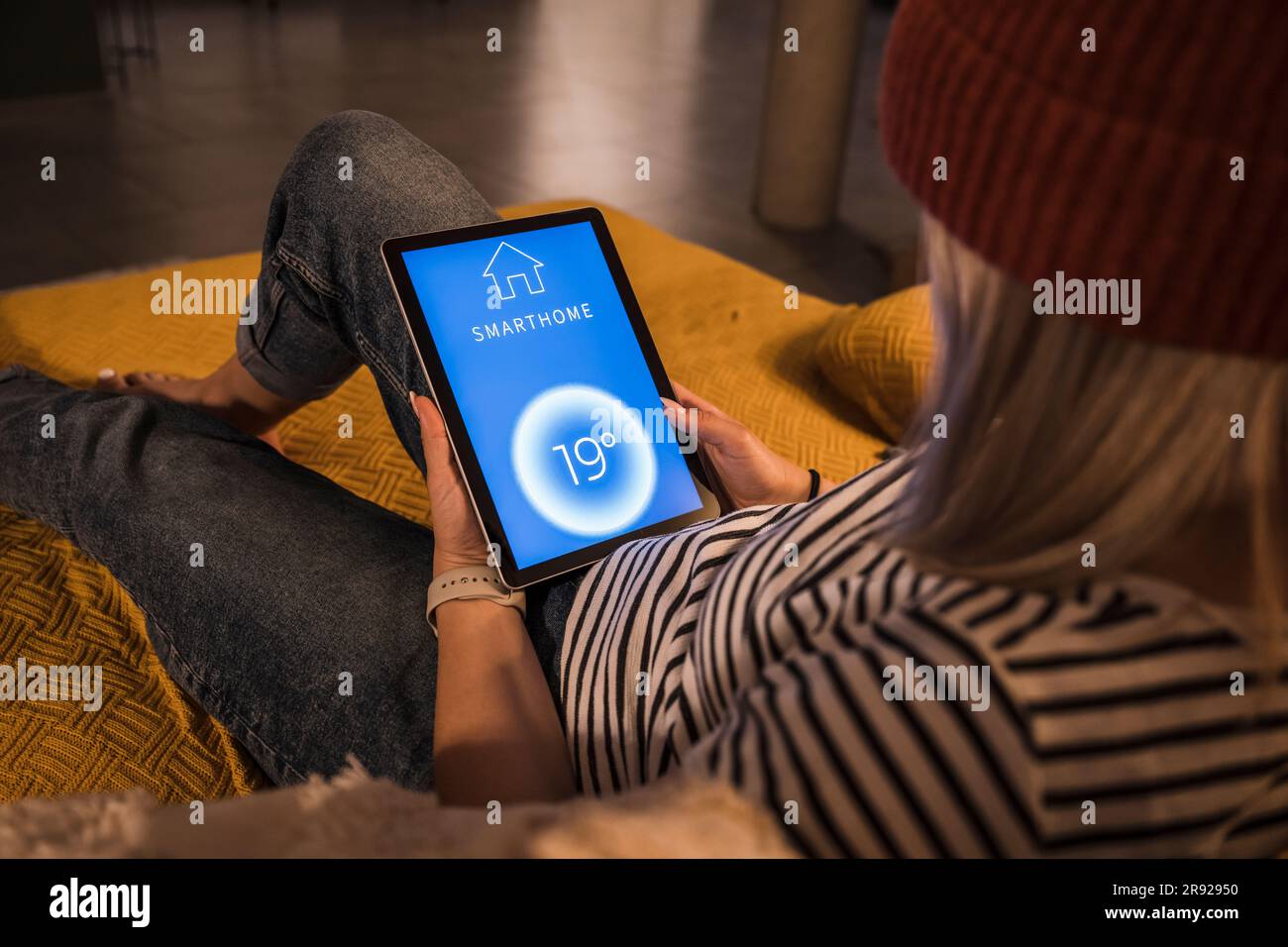 Mujer joven que usa la aplicación de automatización del hogar en la PC de la tableta Foto de stock