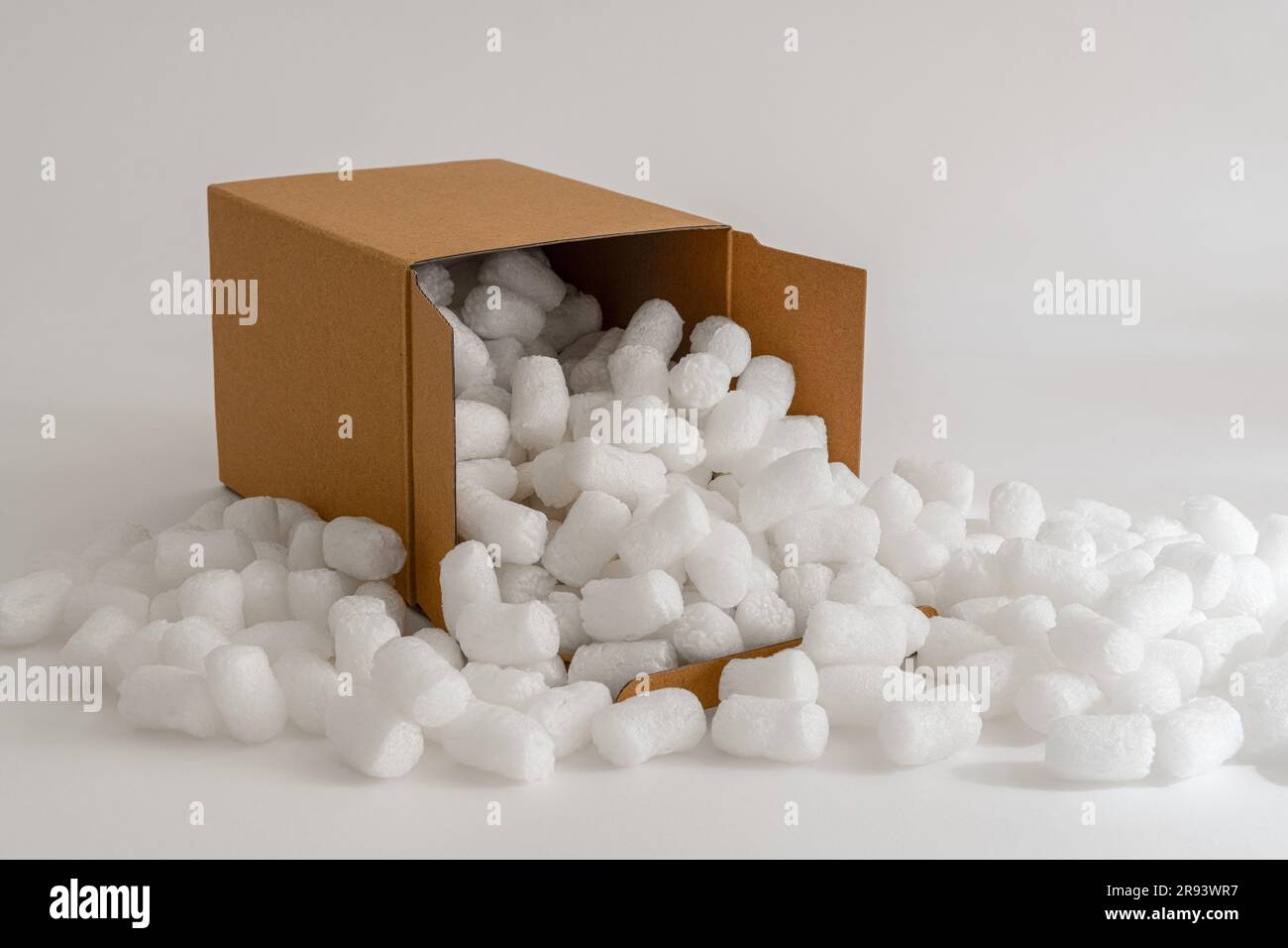 Caja de cartón aislada en el fondo blanco lleno de cacahuetes de embalaje Foto de stock