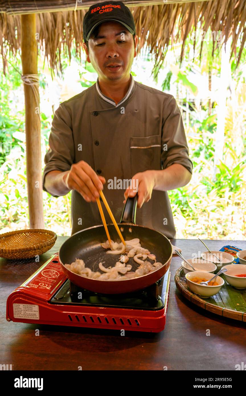 Chef y tutor muestra cómo cocinar auténticos mariscos vietnamitas en la Escuela de Cocina Red Bridge en las afueras de Hoi An, Vietnam. Foto de stock
