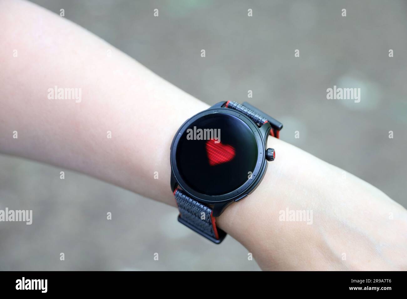 Reloj inteligente en la mano femenina que mide el ritmo cardíaco. Pantalla redonda con aplicación para monitoreo de salud Foto de stock