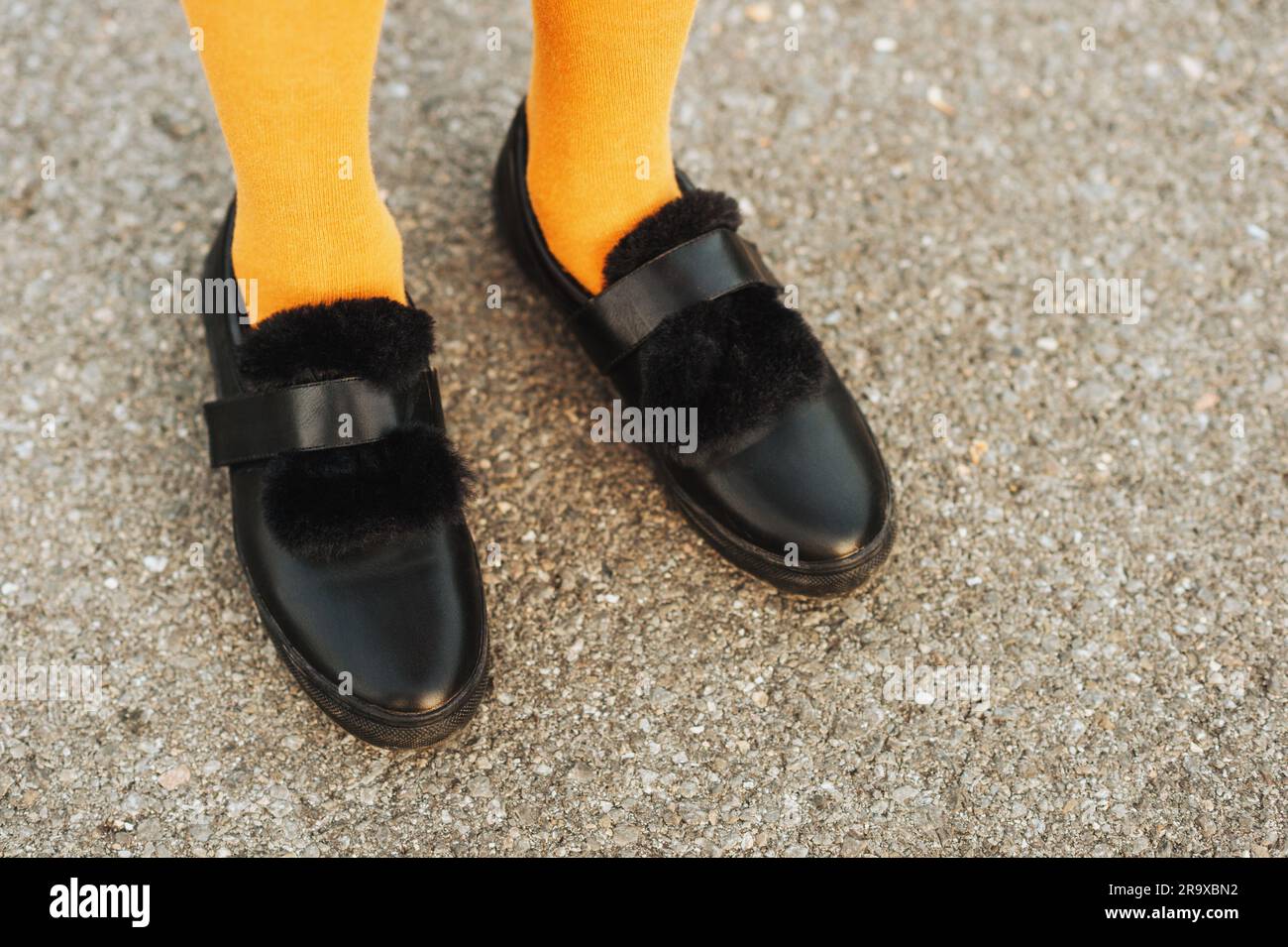 Zapatos de cuero de correa negra con piel sintética medias amarillas en los pies niña Fotografía de stock -
