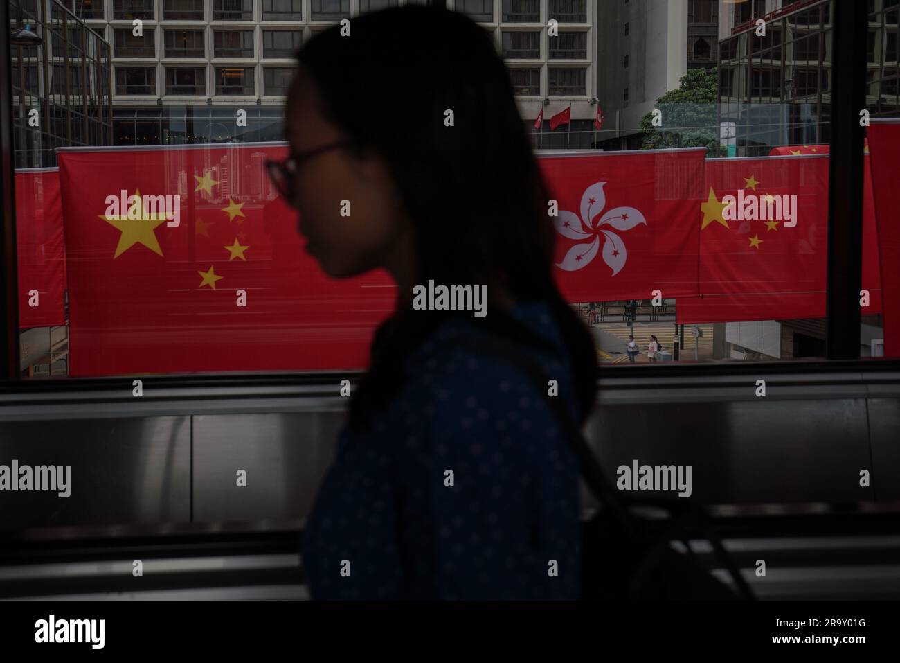 Una mujer pasa por delante de las banderas de China y Hong Kong. A