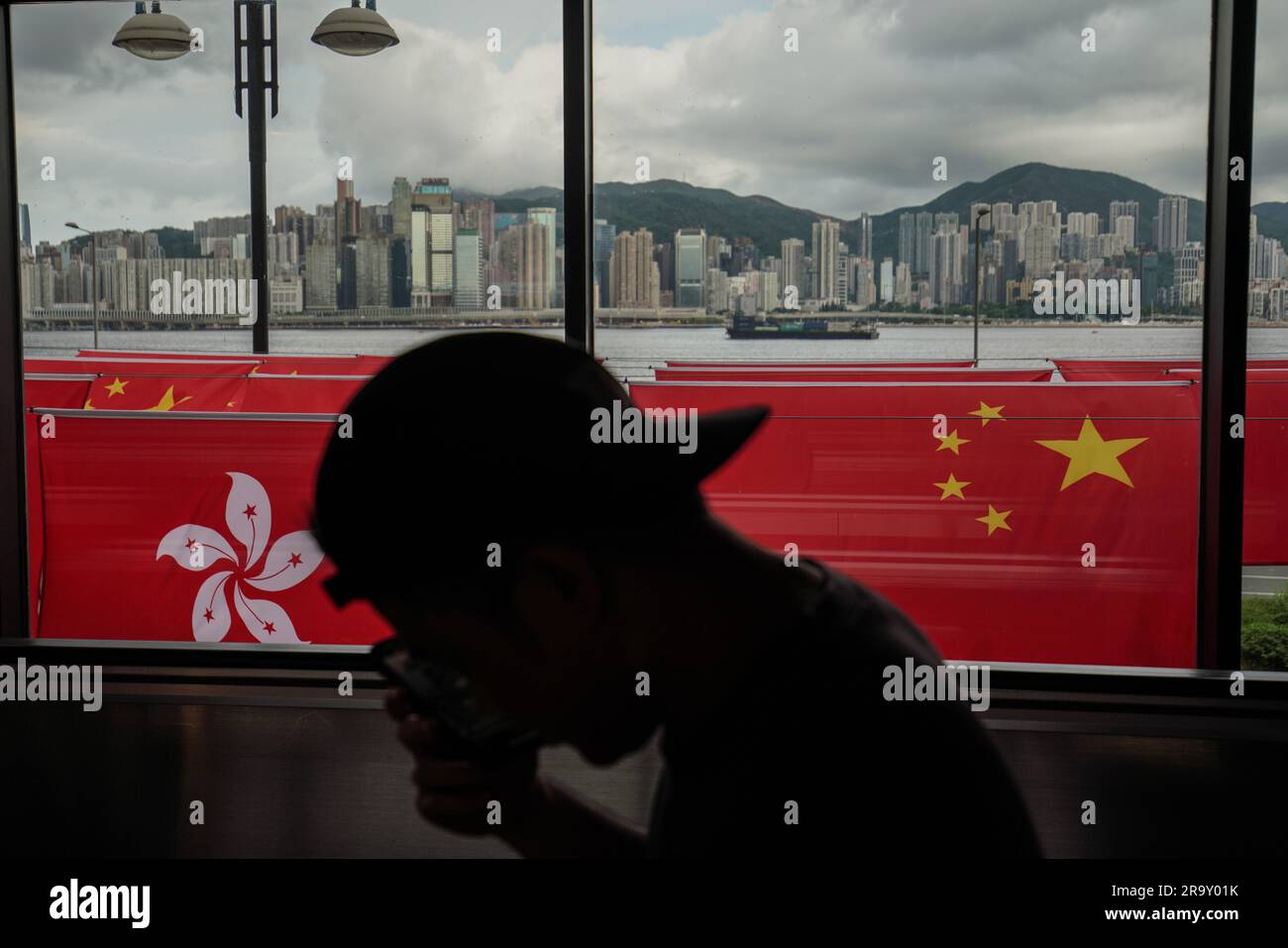 Un hombre pasa por delante de las banderas de China y Hong Kong. A