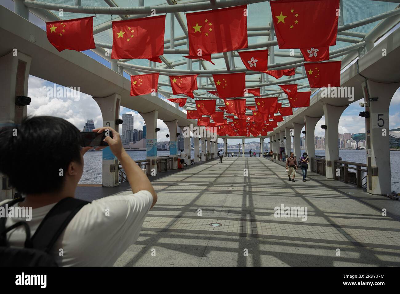 Un hombre toma fotos de banderas de China y Hong Kong en un muelle. A
