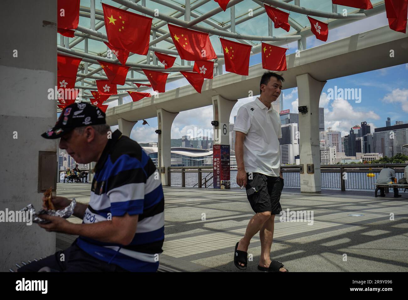 La gente pasa por las banderas de China y Hong Kong en un muelle. A