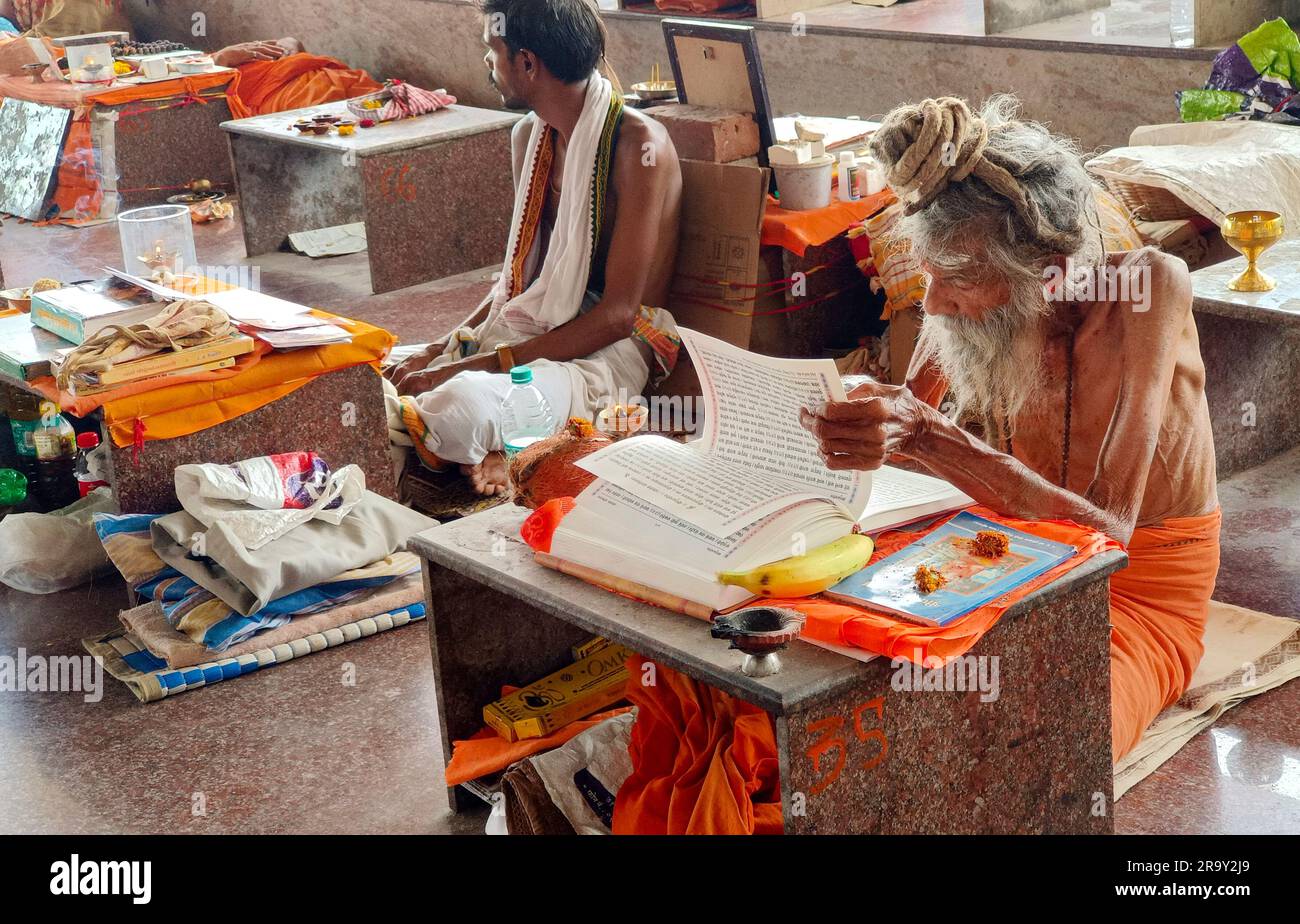 24 de junio de 2023, Sadhu indio de la vejez leyendo las Sagradas Escrituras en Ganagapura, Karnataka, India. Foto de stock