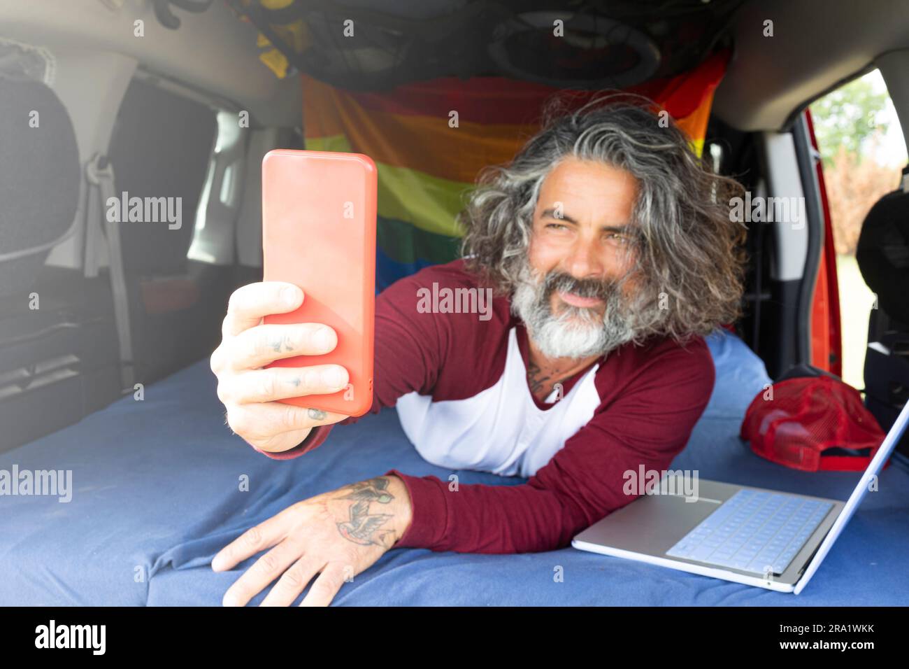 Feliz bloguero de viajes haciendo un selfie en el teléfono inteligente, dentro de minivan - Nómadas digitales que utilizan aplicaciones para teléfonos móviles - Tecnología y concepto de trabajo alternativo Foto de stock