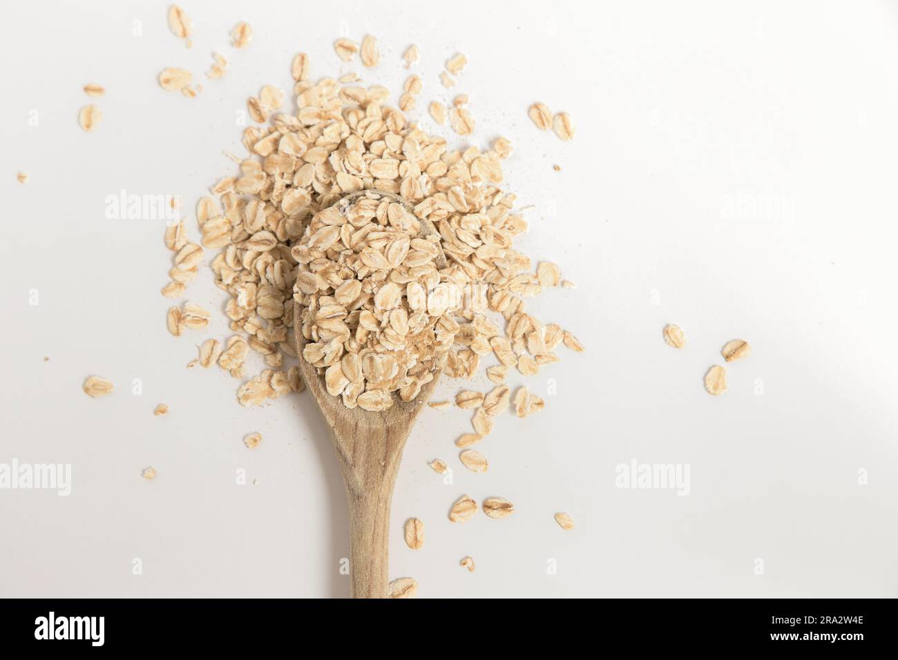 Cuchara de madera llena de copos de avena sobre fondo blanco. Súper alimento rico en nutrientes y que se puede utilizar para varias recetas. Alimentación saludable. Foto de stock