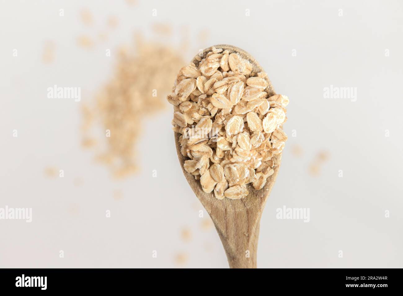 Cuchara de madera llena de copos de avena sobre fondo blanco. Súper alimento rico en nutrientes y que se puede utilizar para varias recetas. Alimentación saludable. Foto de stock