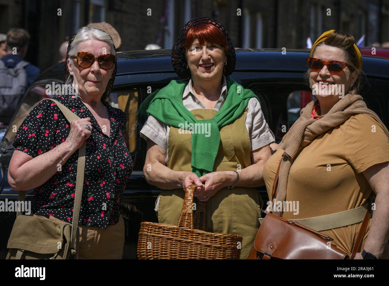 Recreación nostálgica de la historia de vida retro de Haworth 1940 (mujeres de pie de cerca, trajes vintage de los años WW2) - Main Street, West Yorkshire Inglaterra Reino Unido. Foto de stock