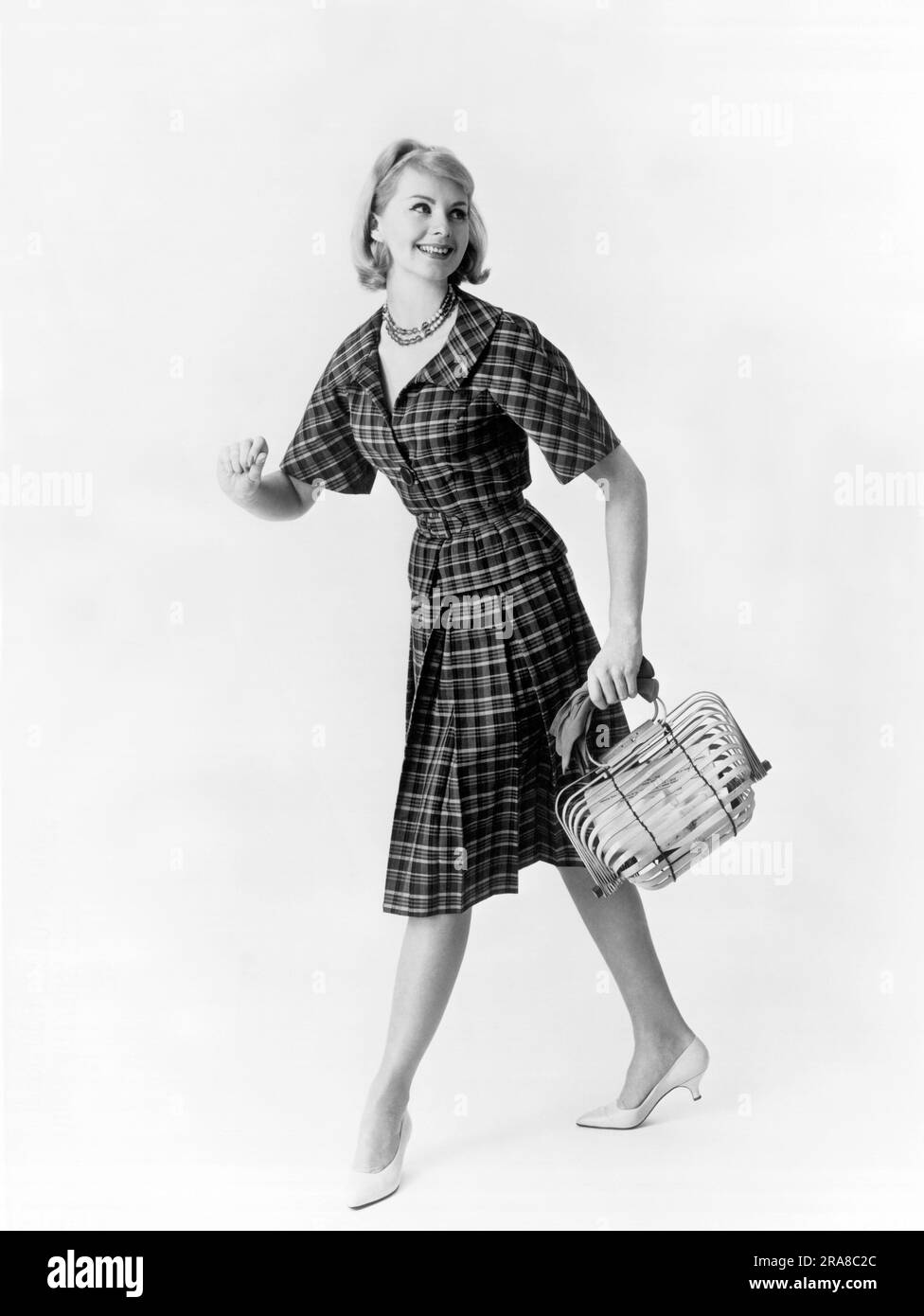 Estados Unidos: c. 1963 Modelo con traje de vichy a cuadros con cintura con cinturón y falda plisada, todo diseñado por Ira Rentner. Foto de stock