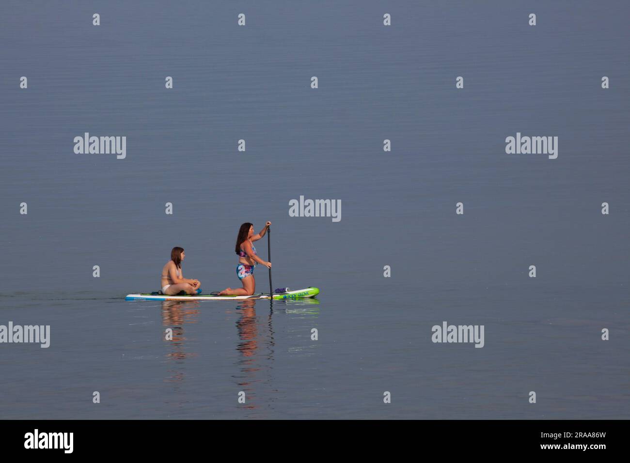 Lexington, Michigan, EE.UU. 1º de julio de 2023. Cuando los estadounidenses comenzaron el fin de semana del Día de la Independencia, dos mujeres se subieron a un paddleboard en el lago Huron. Crédito: Jim West/Alamy Live News Foto de stock
