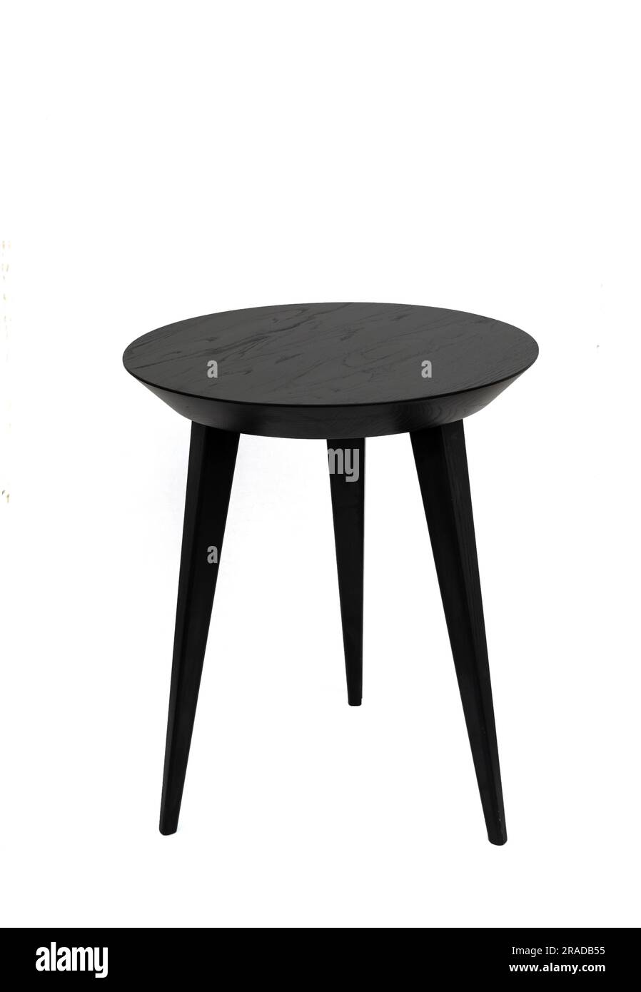 Mesa de centro redonda de madera negra en tres patas con una hermosa textura de madera. Aislado sobre un fondo blanco Foto de stock