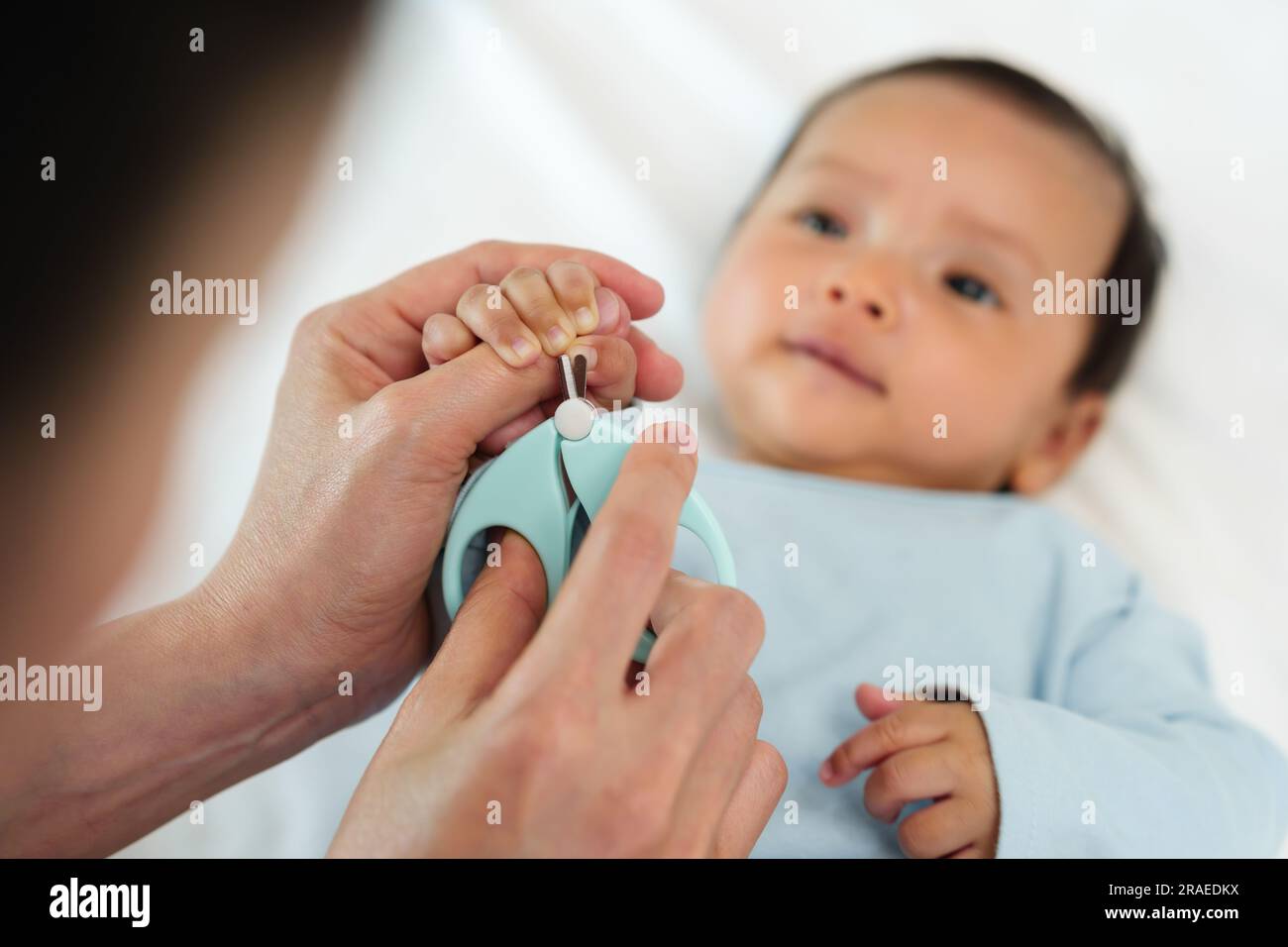 Mamá corta las uñas del bebé con tijeras especiales para niños cerca de  manicura para recién nacidos de fondo gris