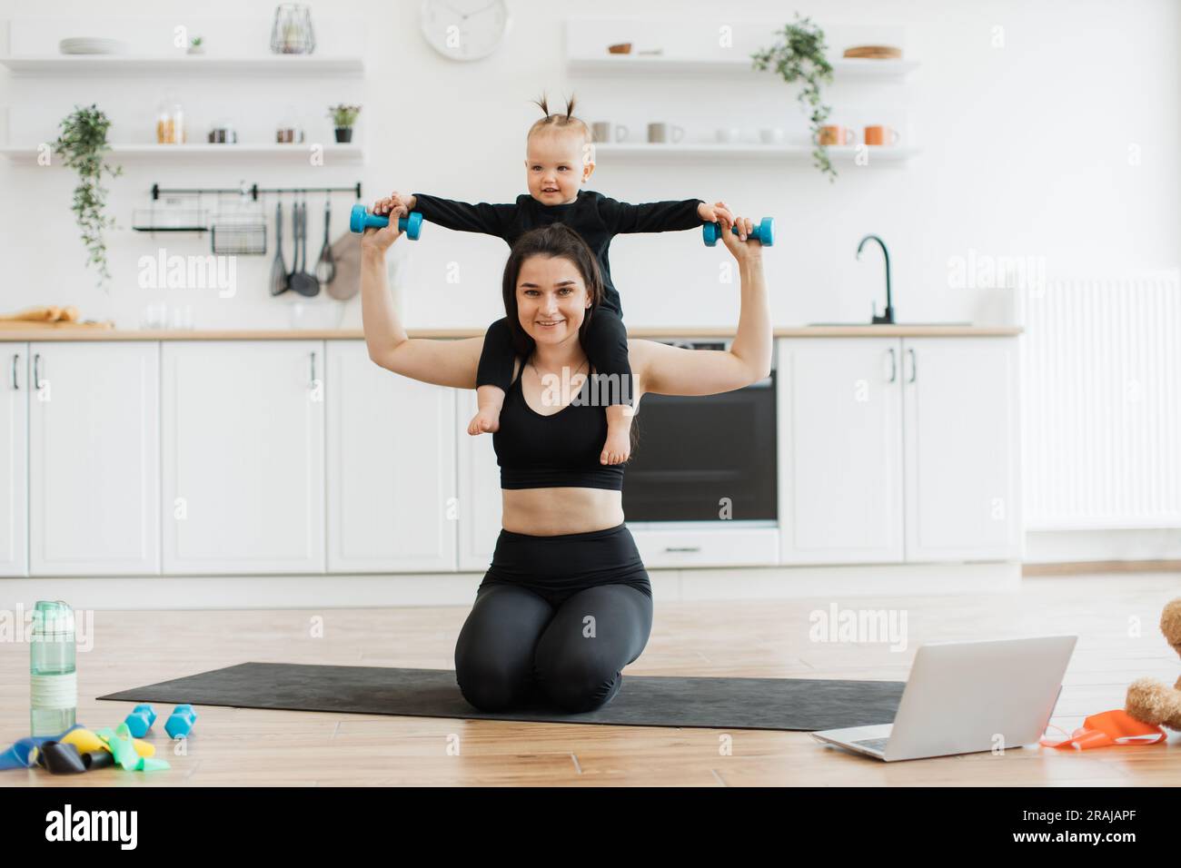 Mujer alegre en ropa de yoga que lleva a la ni a con mancuernas en