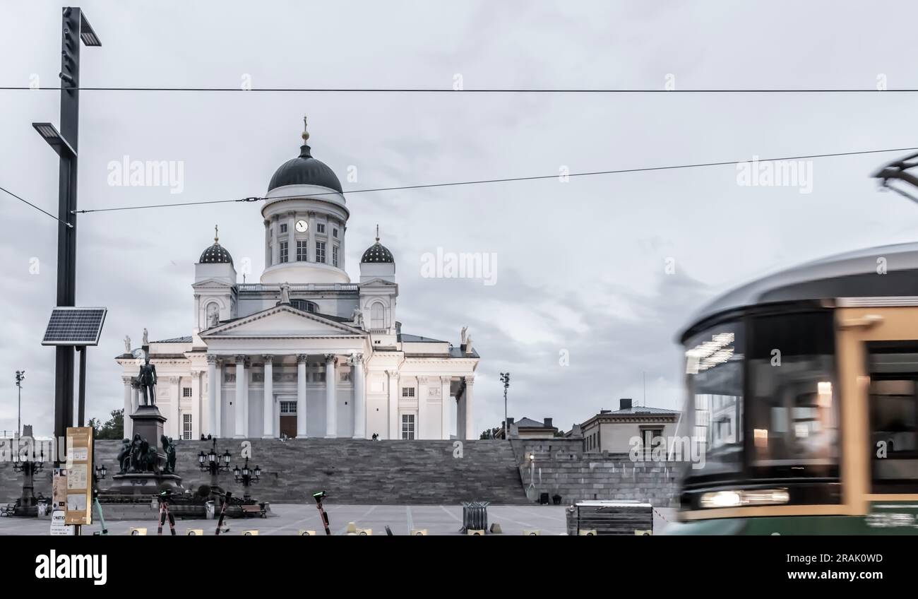 La Plaza del Senado, la estatua de Alejandro II y la Catedral de Helsinki por la noche. En primer plano, un tranvía, una estación de bicicletas de la ciudad y algunos e-scooters. Foto de stock