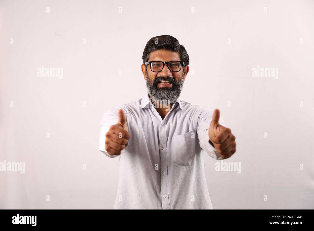 Retrato de un hombre barbudo indio con camisa. Funky Expressions Sentido de logro y logro. Pulgares arriba. Estrategia ganadora. Foto de stock