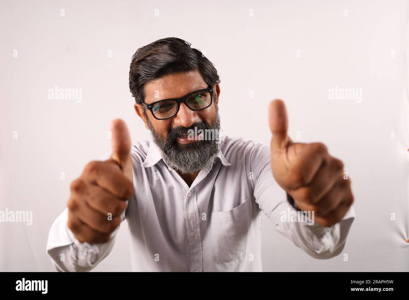 Retrato de un hombre barbudo indio con camisa. Funky Expressions Sentido de logro y logro. Pulgares arriba. Estrategia ganadora. Foto de stock