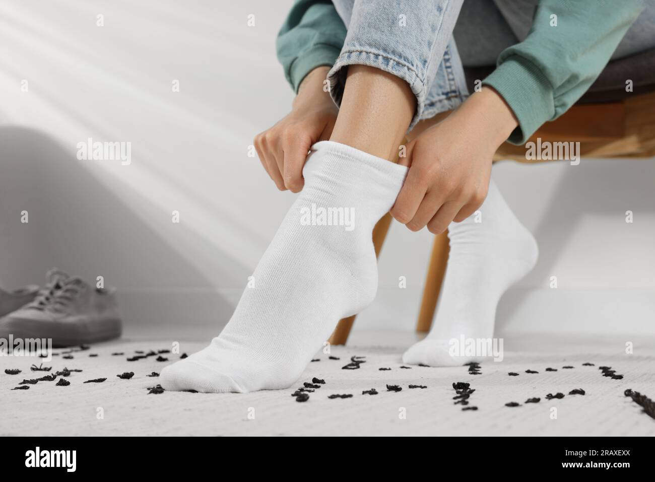 Mujer poniéndose calcetines blancos en casa, primer plano