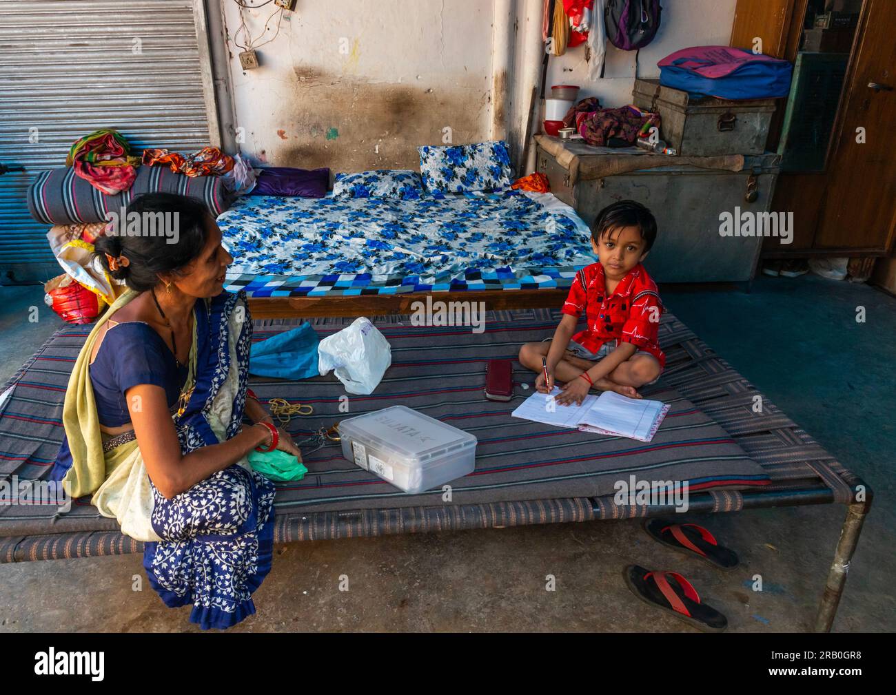 Niño haciendo sus ejercicios escolares con su madre en la vieja Delhi, Delhi, Nueva Delhi, India Foto de stock