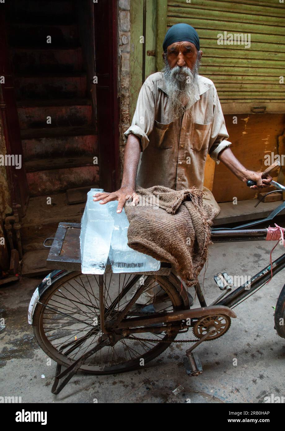 Hombre indio llevando hielo en su bicicleta en la vieja Delhi, Delhi, Nueva Delhi, India Foto de stock