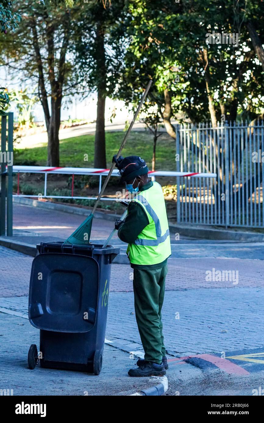 Barredora callejera africana o trabajador que lleva chaqueta de alta visibilidad y monos que limpian el medio ambiente en la ocupación del concepto de Sudáfrica Foto de stock