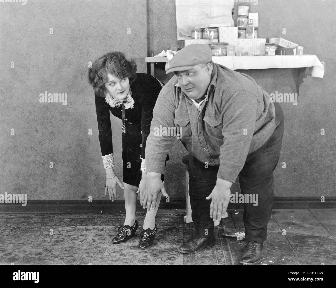 Hollywood, California: c. 1920 Los actores de cine silencioso Dorothy Devore y Frank Alexander comparan las habilidades de tocar los dedos de los pies. Foto de stock