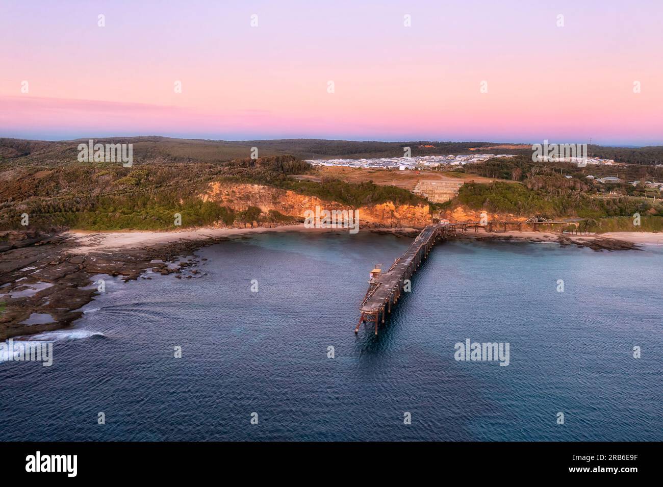 Largo embarcadero histórico en la playa de Middle Camp de la ciudad de la bahía de Catherine Hill en la costa del Pacífico de Australia al amanecer. Foto de stock