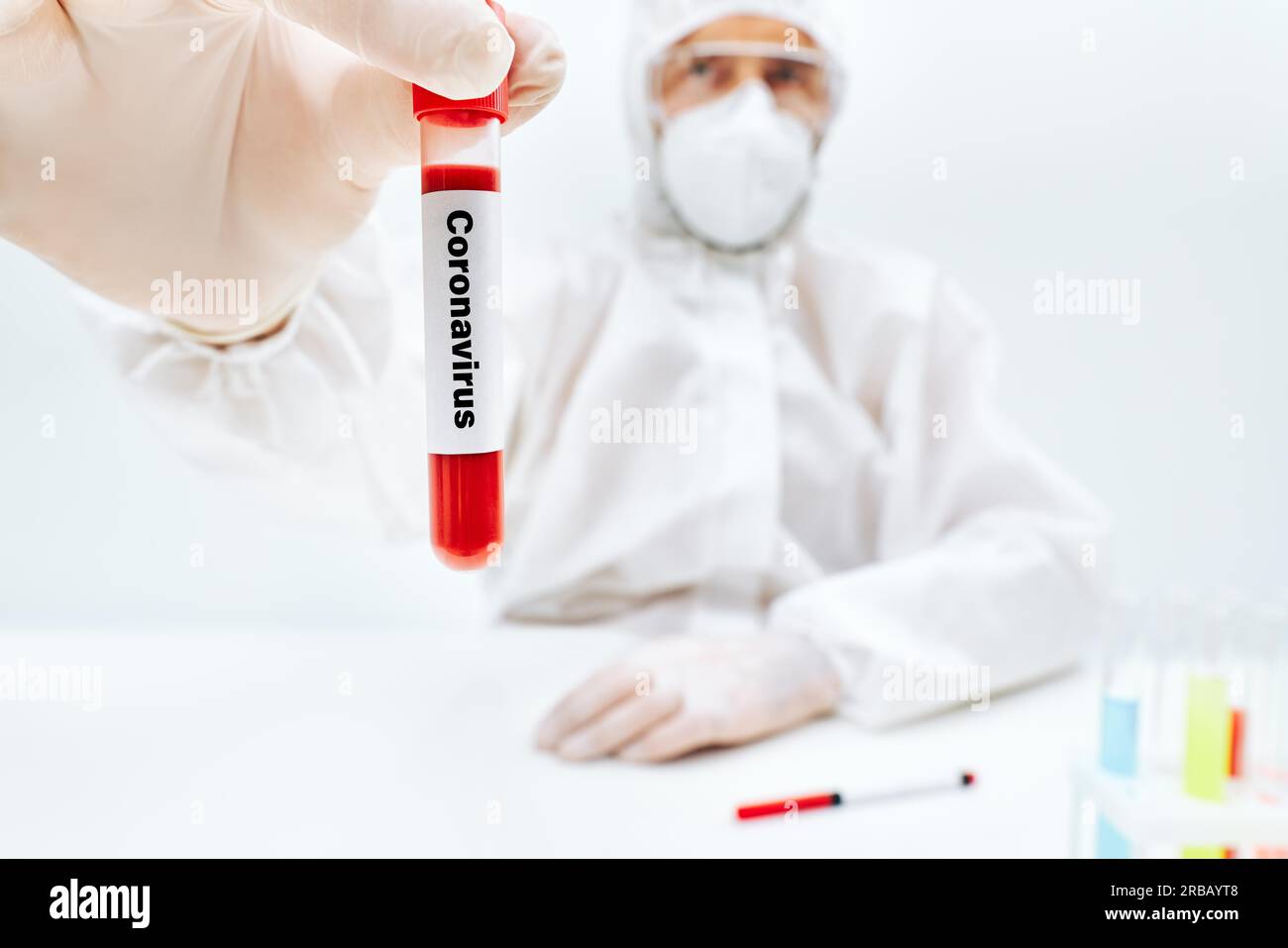 Médico en traje protector que muestra el tubo de prueba de sangre infectada por coronavirus. Diagnóstico, infección Foto de stock