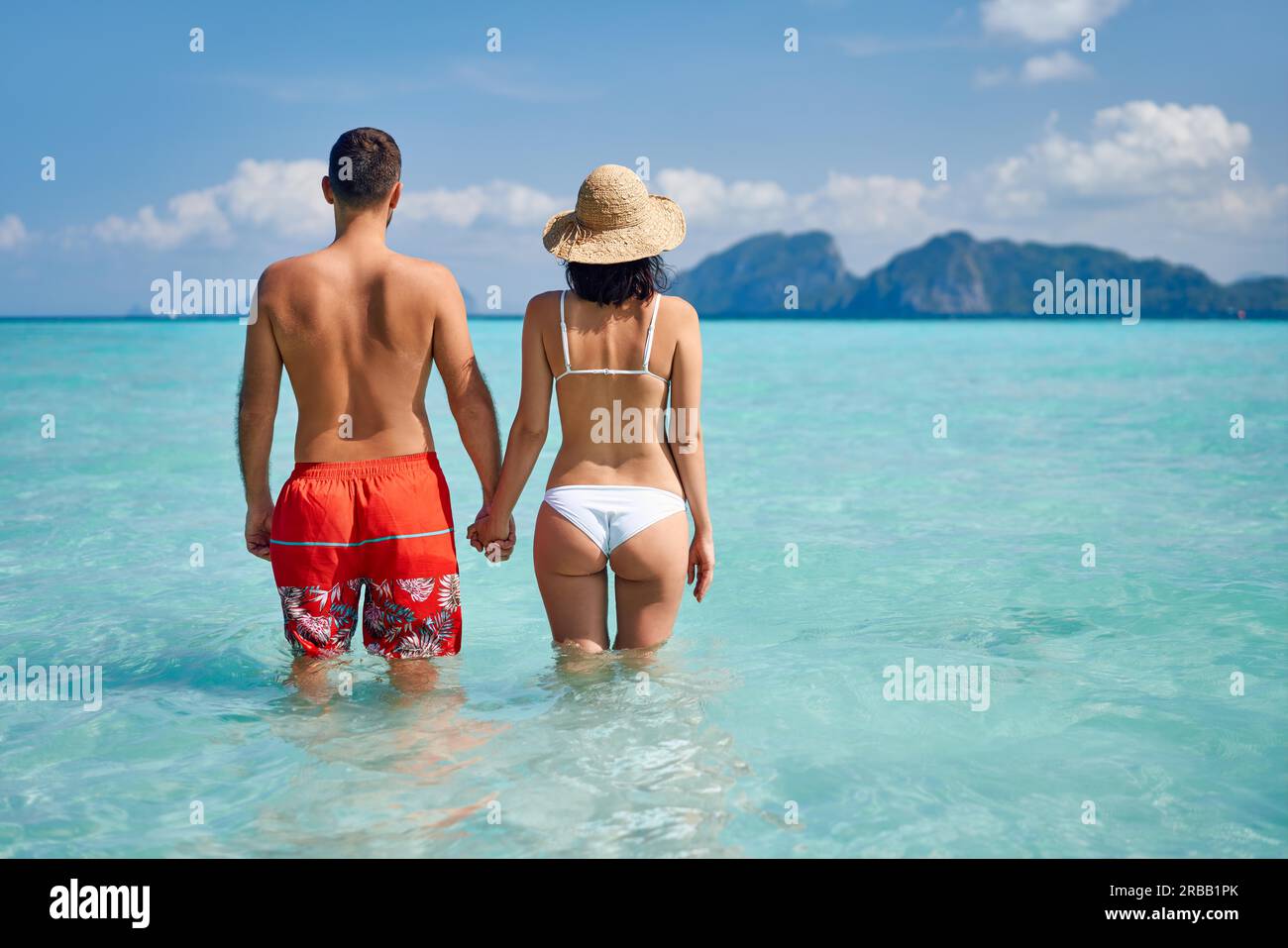 Vista trasera de una feliz pareja enamorada disfrutando del agua caliente del océano tropical. Concepto de vacaciones de verano, destino de viaje. Espacio de copia Foto de stock