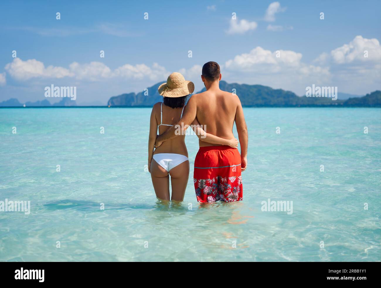 Pareja romántica enamorada abrazándose en la playa tropical disfrutando del agua caliente del océano. Concepto de vacaciones de verano, destino de viaje. Vista trasera Foto de stock