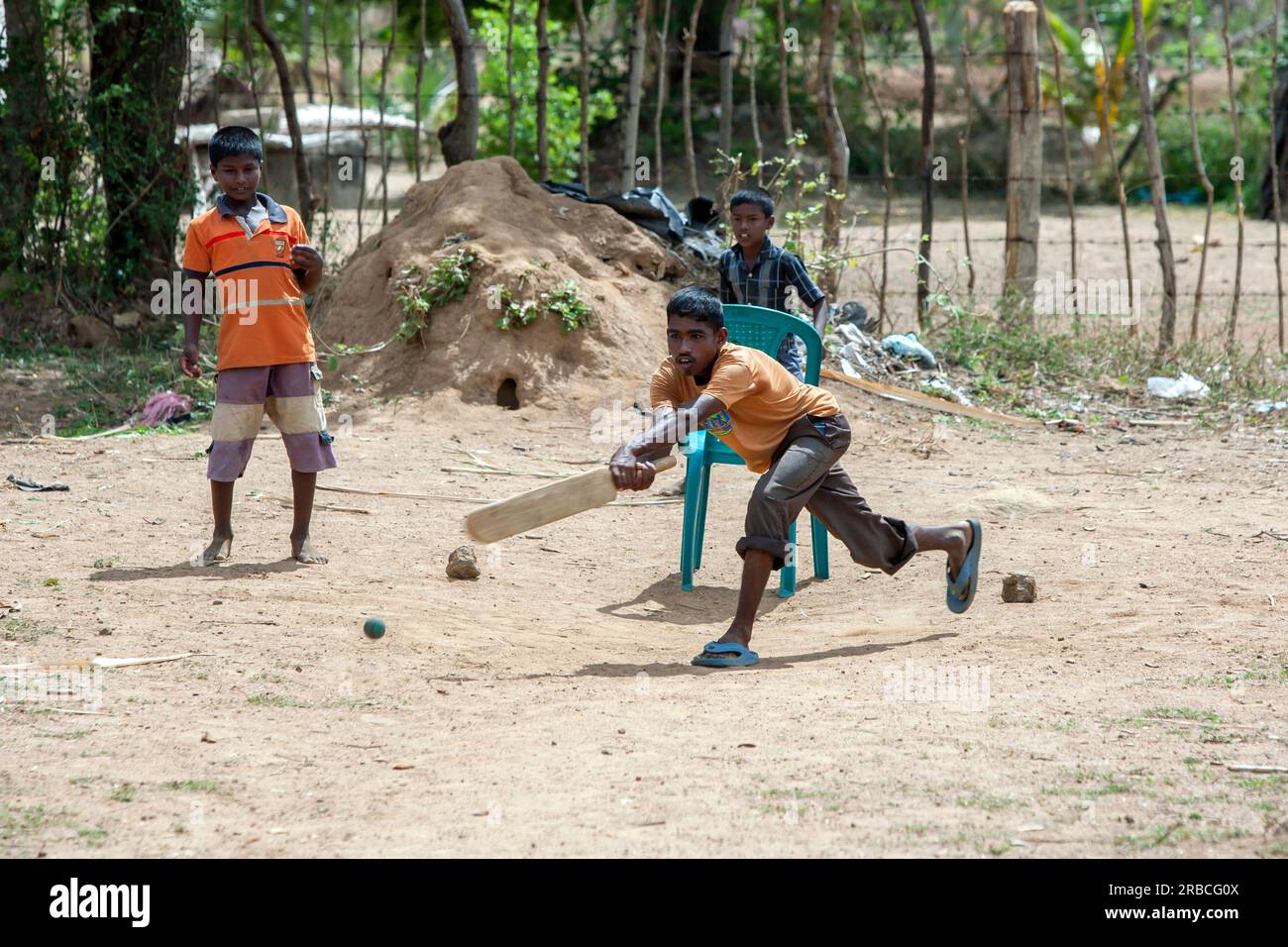 Un joven jugador de críquet se balancea en una entrega durante un partido en un pueblo cerca de Pottuvil en la costa este de Sri Lanka. Foto de stock
