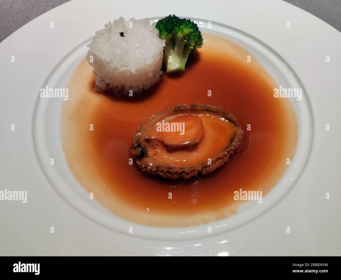 abalone estofado fresco con arroz y brócoli en el plato blanco Foto de stock