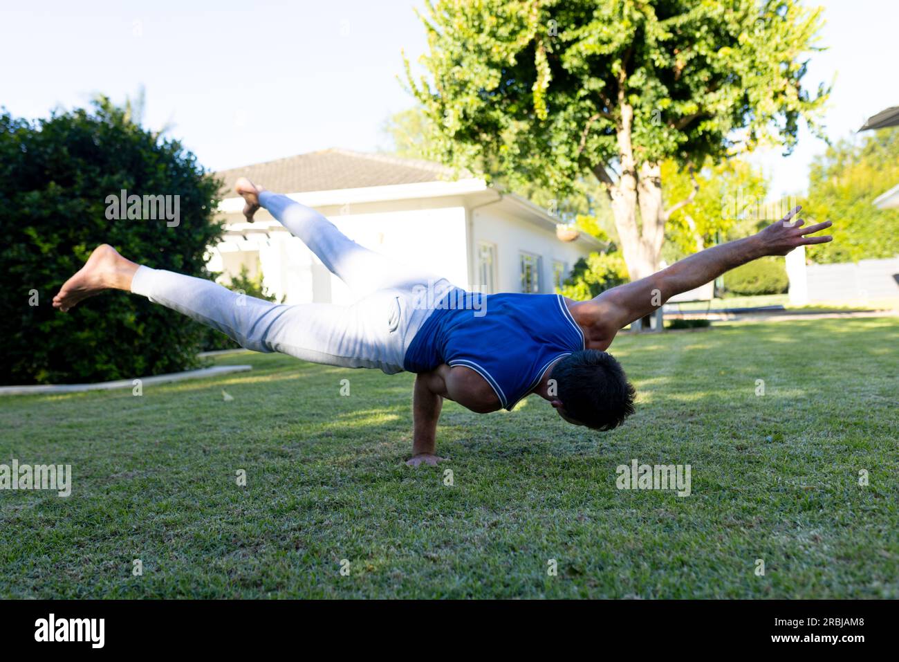 Hombre caucásico practicando yoga y acrobacias en jardín soleado