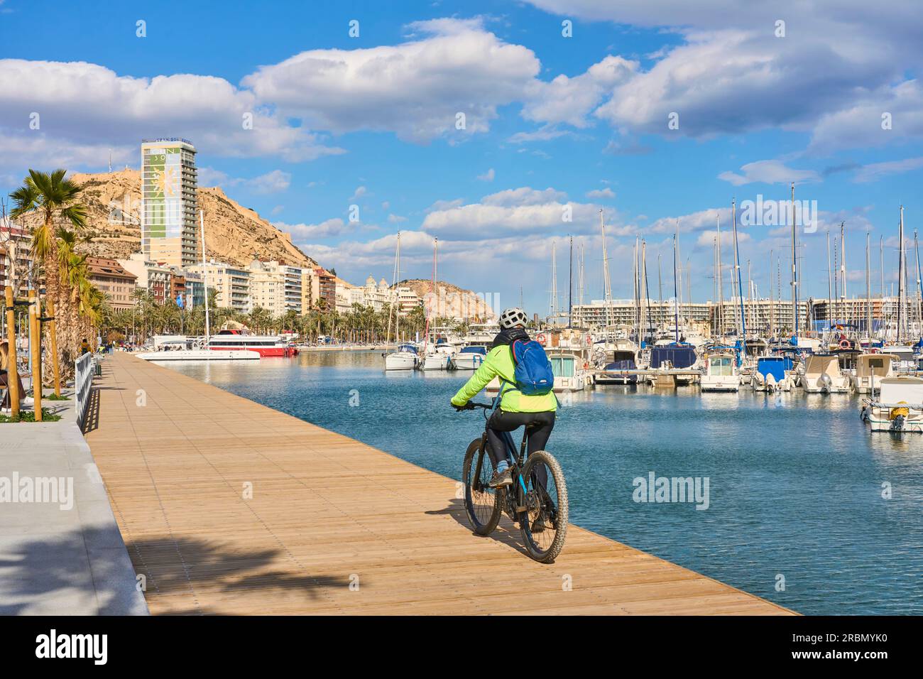 Buena mujer senior en bicicleta en un día fresco de primavera con su bicicleta eléctrica en la costa de Alicante, Costa Blanca, España Foto de stock