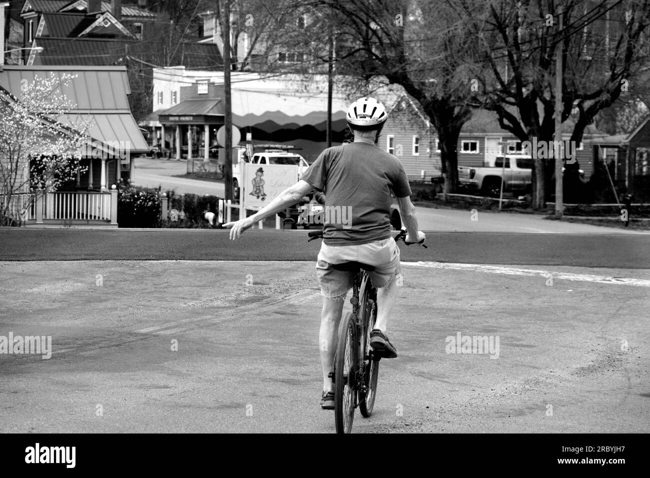 Un hombre mayor monta su bicicleta a lo largo de una calle de la ciudad en Abingdon, Virginia, EE.UU. Foto de stock