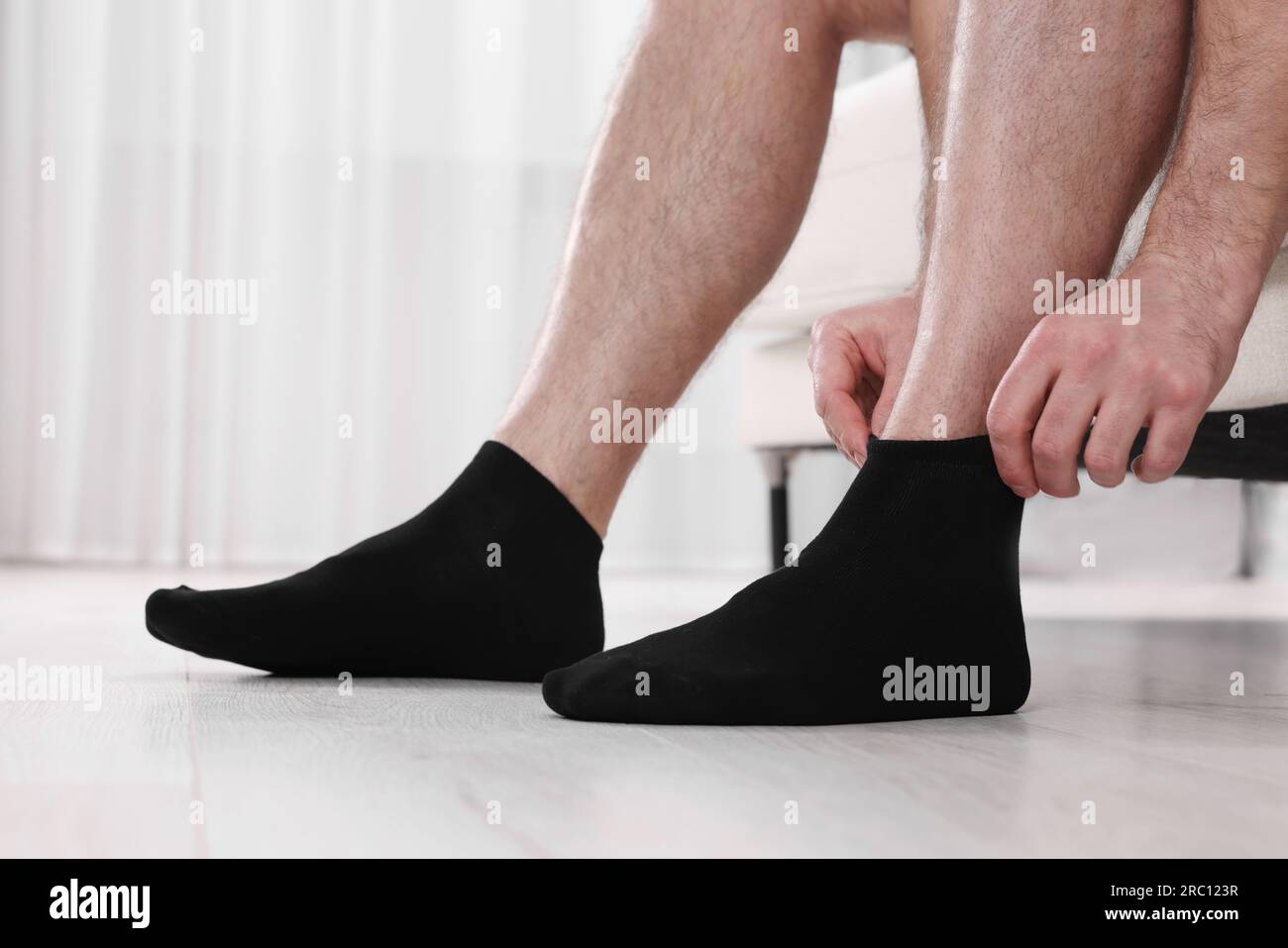 Hombre poniéndose calcetines negros en casa, closeup Fotografía de