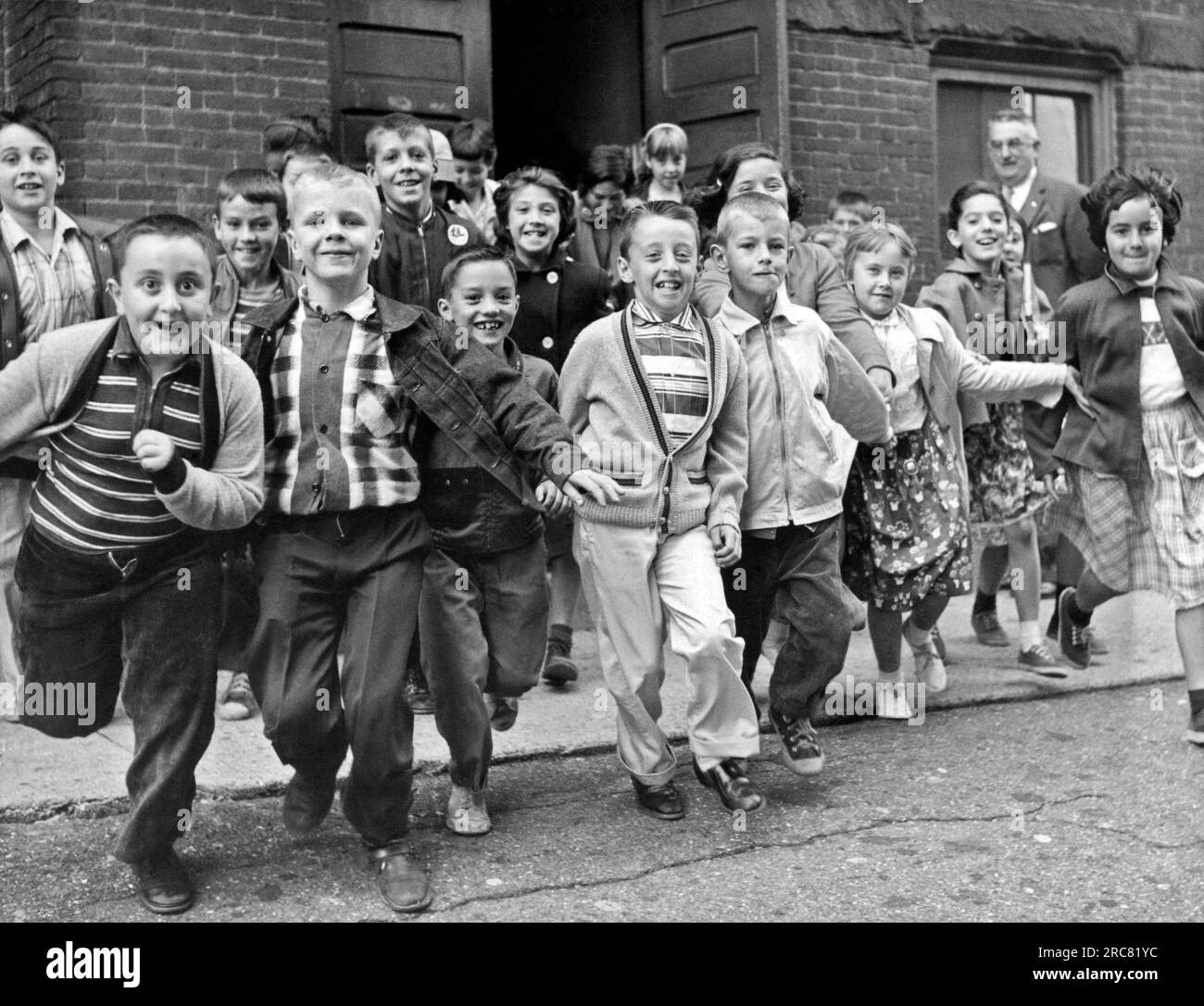 Estados Unidos: c. Junio, 1954. Los estudiantes salen corriendo del edificio de la escuela para las vacaciones de verano en el último día de clases. Foto de stock
