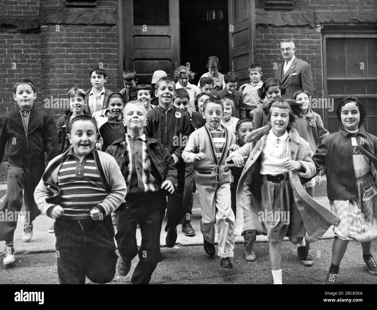 Estados Unidos: c. Junio, 1954. Los estudiantes salen corriendo del edificio de la escuela para las vacaciones de verano después del último día de clases. Foto de stock