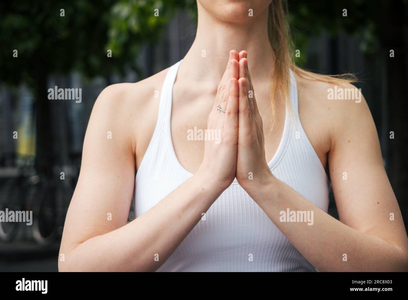 mujer joven practicando yoga y haciendo namaste o anjali mudra con sus manos Foto de stock