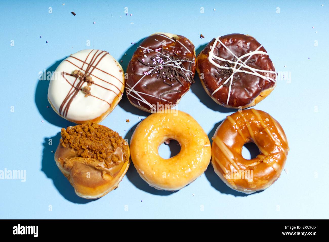 Deliciosos donuts sobre un fondo azul claro, filas de patrón de donuts, variedad de donuts Foto de stock