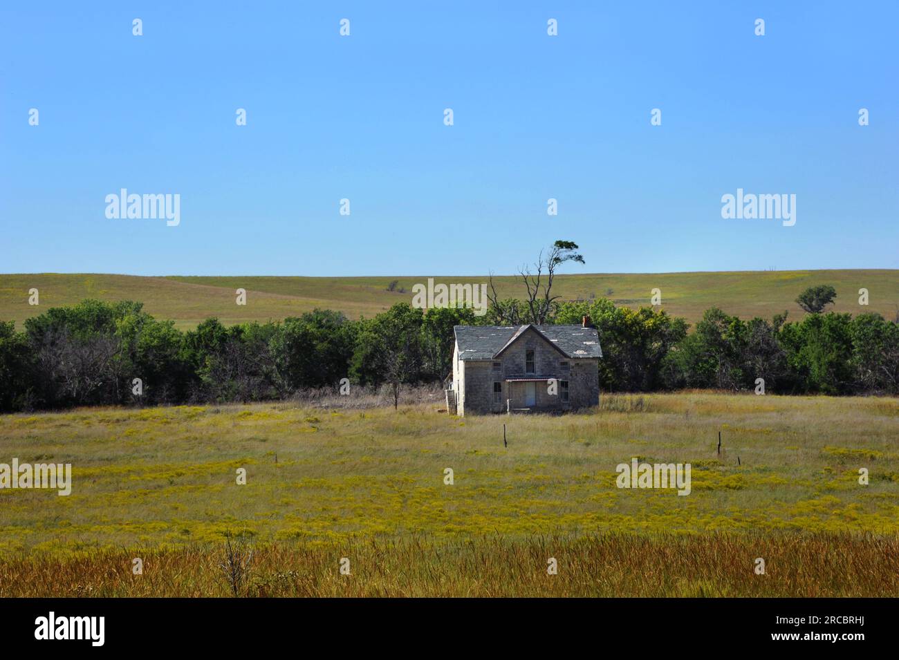 Lone, desierta, casa de piedra se encuentra en la pradera abierta en Kansas. Casa de la granja es de dos pisos y de madera. La pintura blanca está agrietada y pelada. Foto de stock