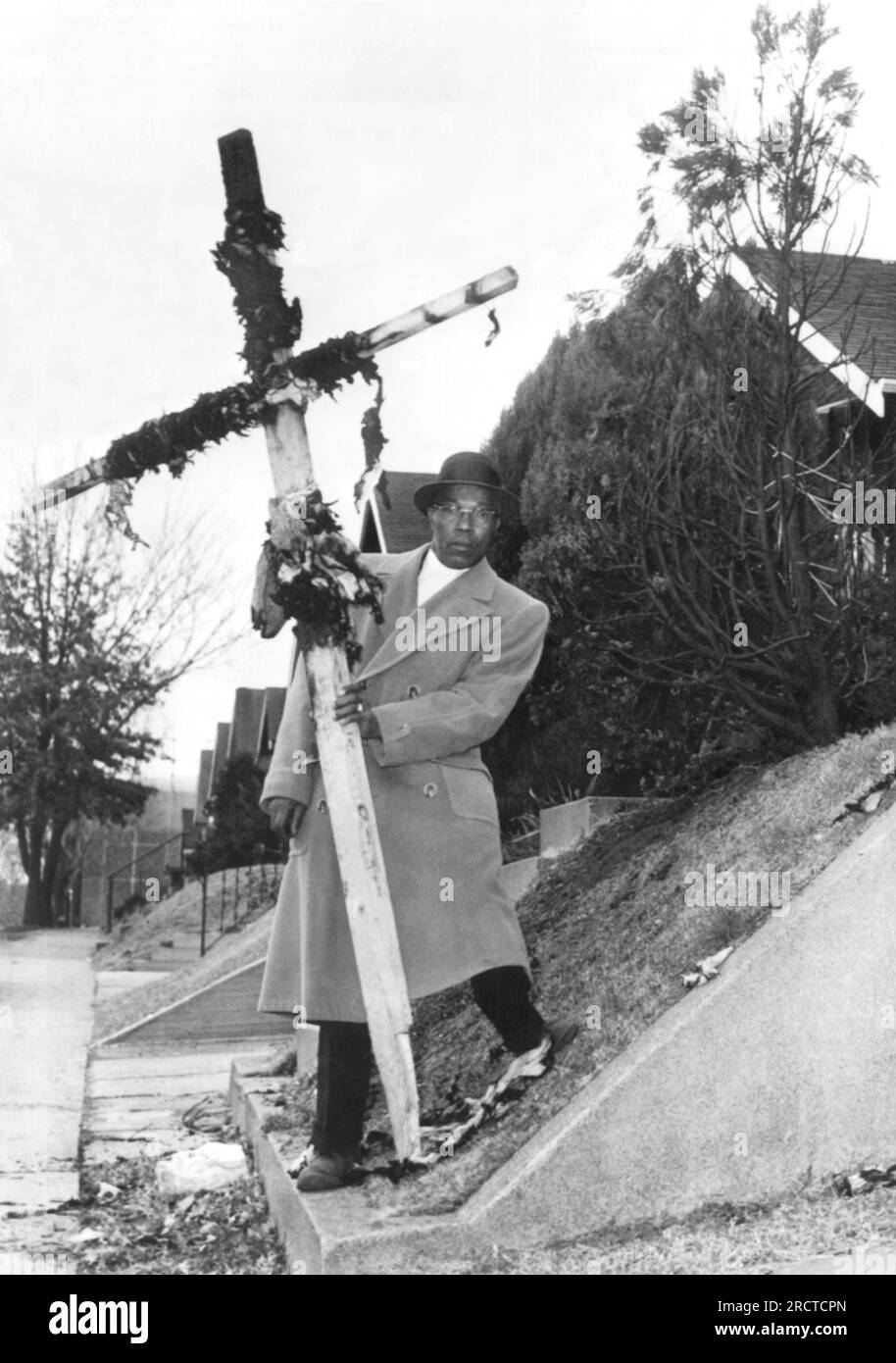St Louis, Missouri: 8 de diciembre de 1960 Leon Butler sostiene una cruz carbonizada que fue quemada en su césped frontal en el último de una serie de eventos de acoso desde que su familia se mudó a un barrio blanco hace cuatro semanas. Foto de stock
