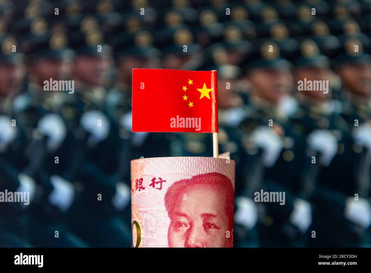 Un rollo de billetes de banco chinos y la bandera nacional con un fondo militar. Un concepto chino de gasto de armas, modernización y construcción. Foto de stock