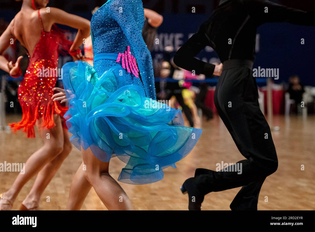 bailarinas en vestido rojo y azul y hombre en vestido negro, concurso de dancesport, baile latino Foto de stock
