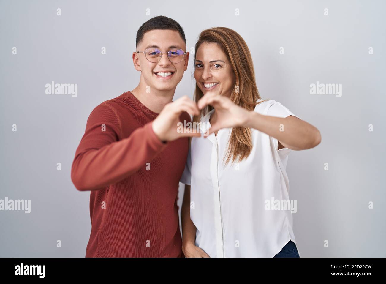 Madre e hijo de pie juntos sobre fondo aislado sonriendo en amor haciendo  forma de símbolo de corazón con las manos. concepto romántico Fotografía de  stock - Alamy