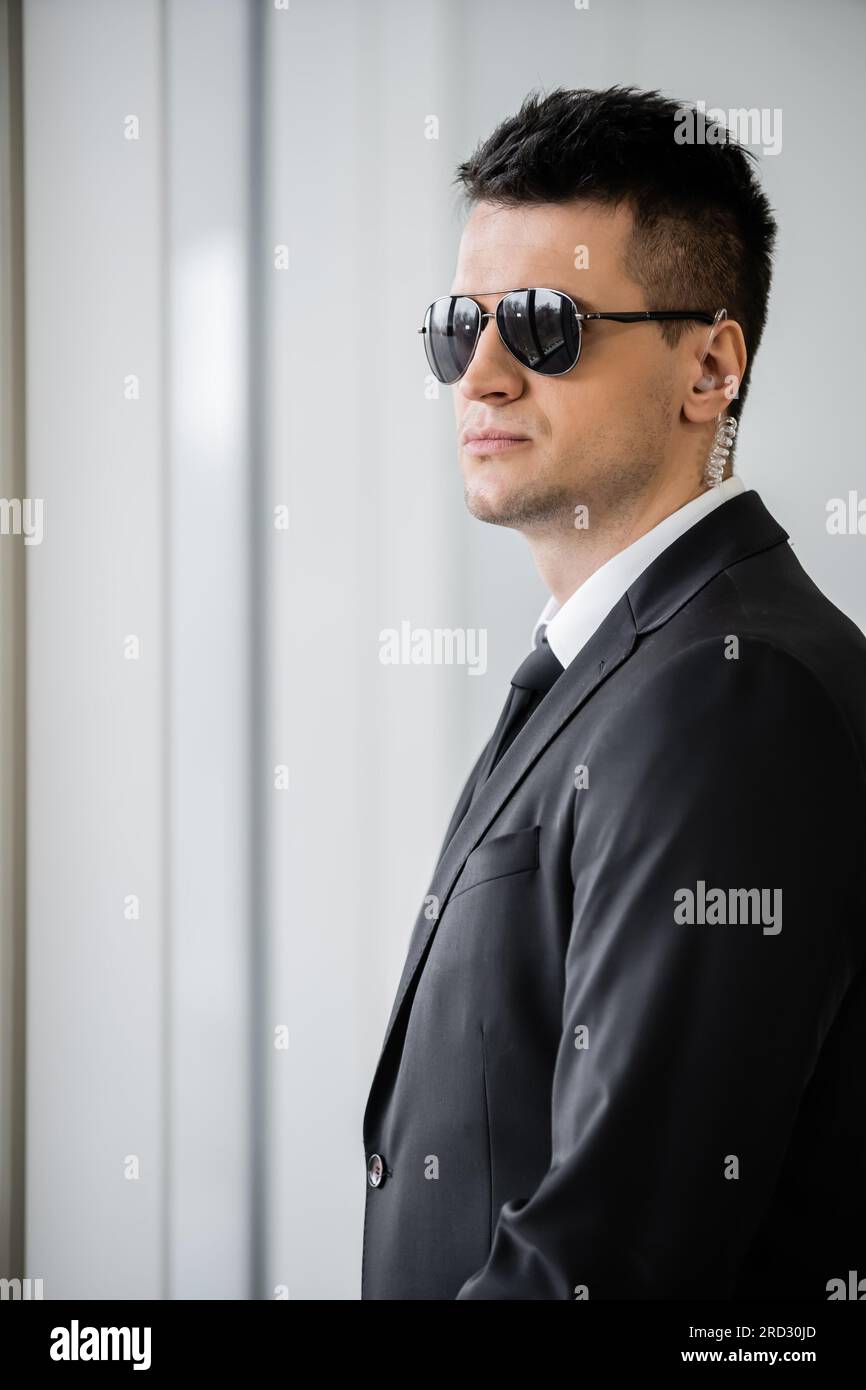 disparos profesionales, guardaespaldas con auricular, hombre guapo en gafas de sol y traje negro con corbata, seguridad del hotel, gestión de seguridad, vigilante Foto de stock